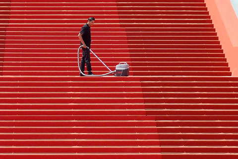 Mann staubsaugt Treppe mit rotem Teppich
